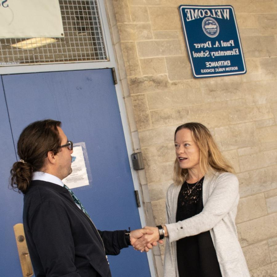 UMass Boston education staff shake hands with staff at the Dever Elementary school.